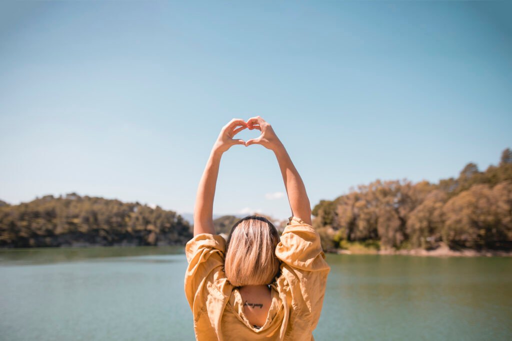 unrecognizable woman showing heart gesture